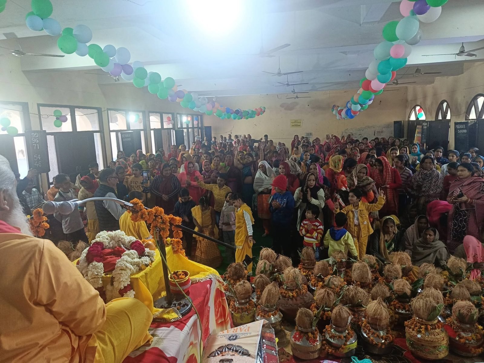 A hall filled with families and rows of decorated kalash